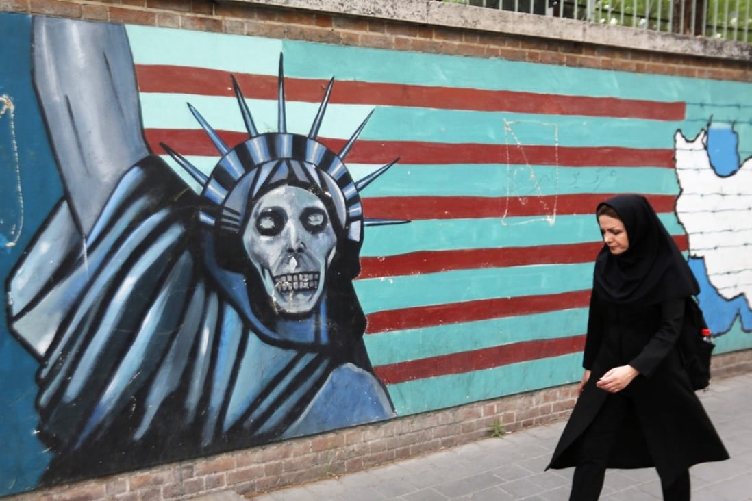 A woman walks past a mural on the wall of the former US embassy in the Iranian capital Tehran on Tuesday. Photo: AFP