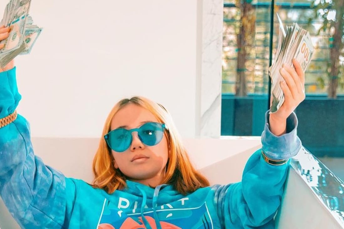 Lil Tay, lying in a bathtub, holds up wads of US$100 bills in one of the controversial videos of her posted online. Photo: courtesy of Instagram