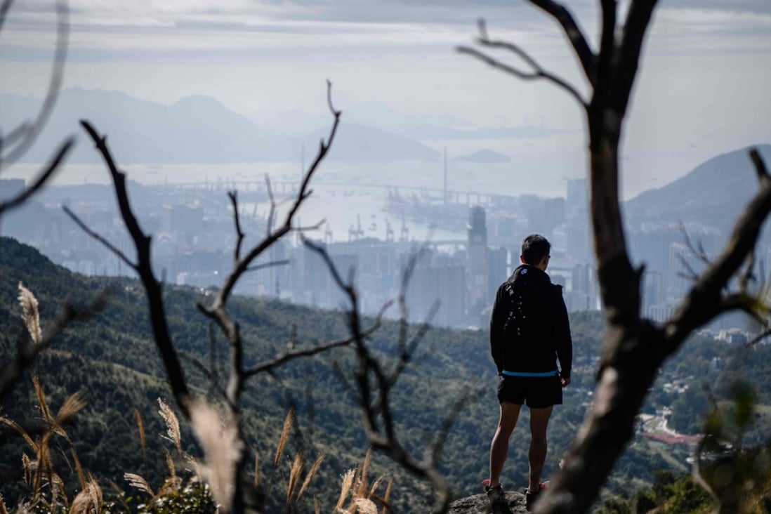 Trail runner Stone Tsang looks out over Hong Kong from Tai Mo Shan. Beijing has made the protection of mountains, forests, rivers and farmland a priority under its 2035 environmental plan and Hong Kong can learn from such schemes, particularly after the “Greater Bay Area” integration plan is unveiled next month. Photo: AFP