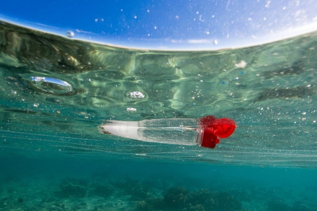 A discarded plastic bottle floats in the ocean over a coral reef. Photo: Alamy