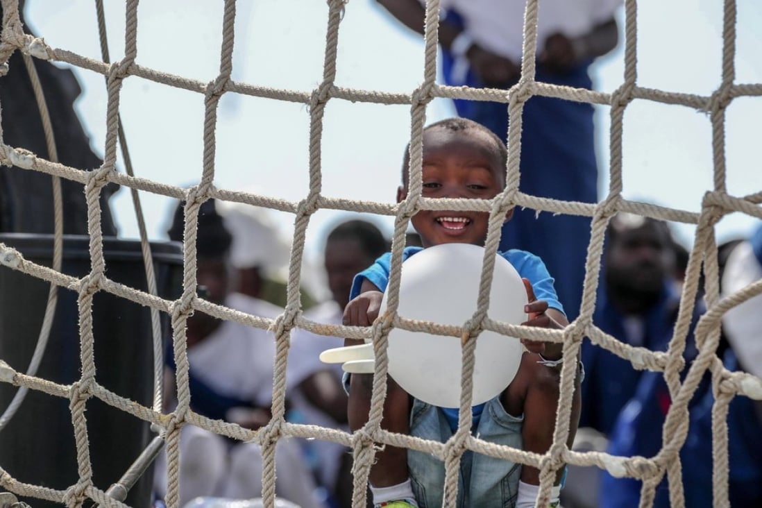 A child plays with a rubber glove on board the Spanish Navy 'Numancia' ship in Palermo, Italy. Photo: EPA