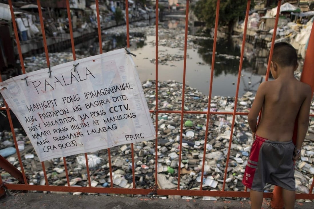 A boy looking at a garbage-filled waterway in Manila. The blanket of trash on a creek that flows between the makeshift homes of a Manila slum is so dense it appears one could walk across it like a paved street. Photo: AFP