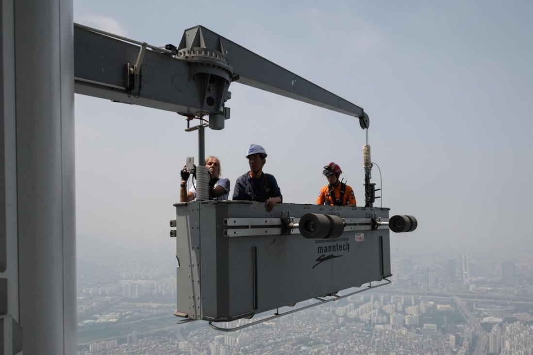 'Urban climber' Alain Robert of France is hoisted to a deck of the Lotte World Tower after scaling the exterior of the building, in Seoul on June 6. Photo: AFP