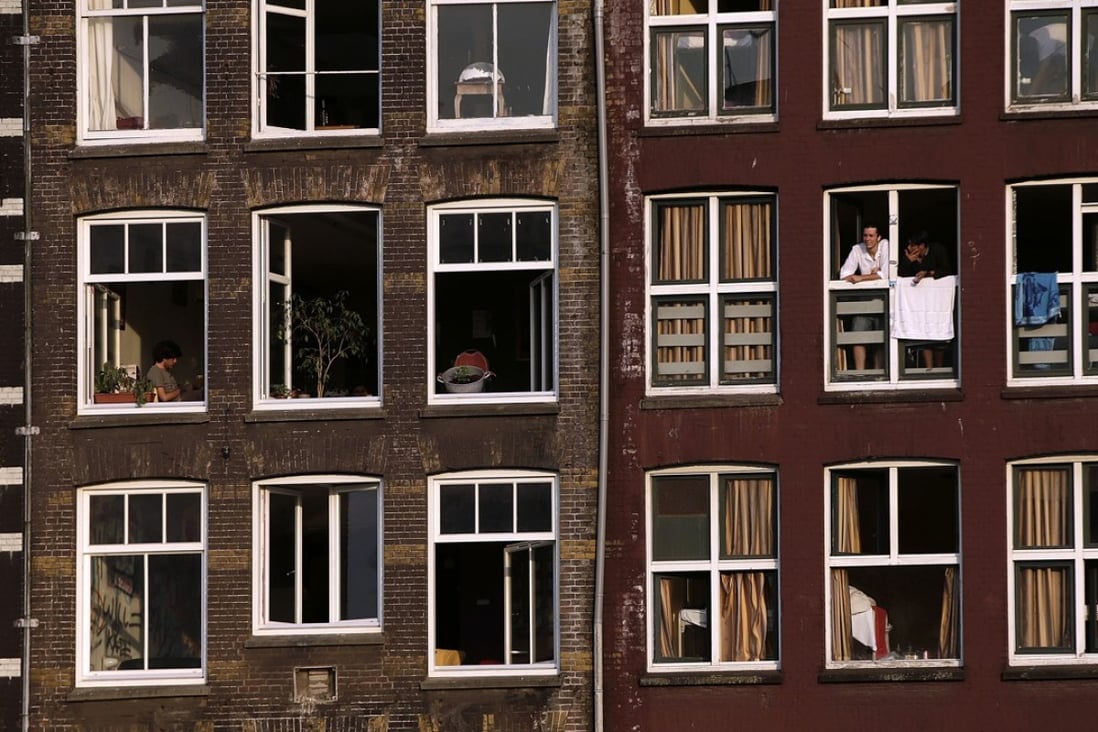 A resident looks out from the window of a residential property in Amsterdam. Housing prices in the capital city have soared. Photo: Bloomberg