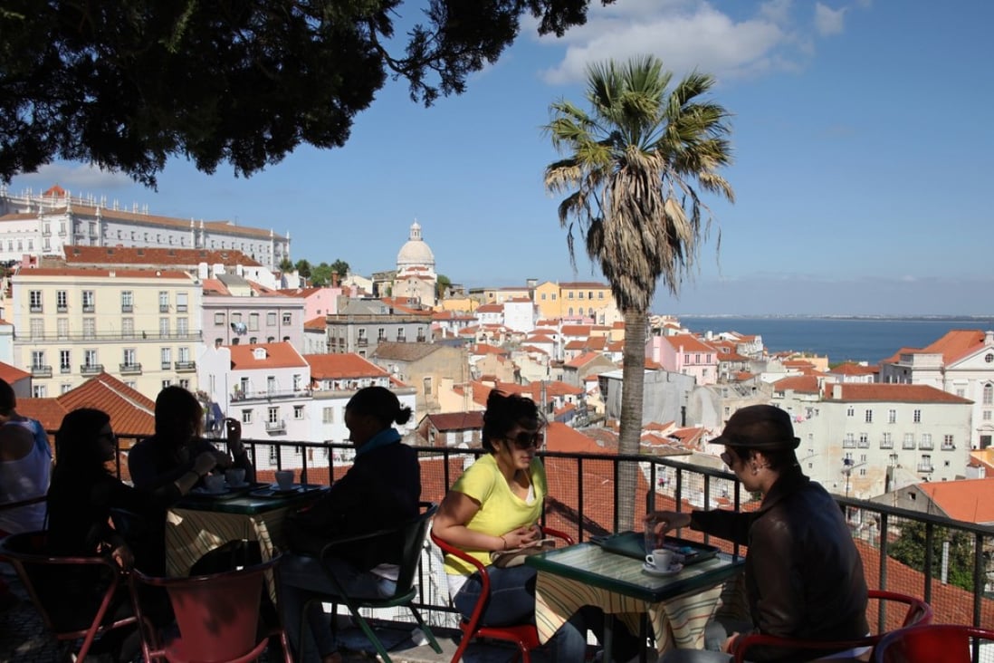 Tourists sit in the shade at an outdoor cafe overlooking Lisbon's Alfama old quarter along the Tagus river in Portugal. Photo: AP