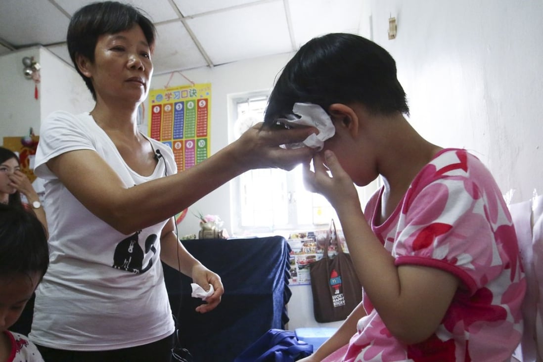 Lin Xiaohong helps her daughter Chiu Ka-wai (right) stay cool during a hot day at their home in Tai Kok Tsui. Photo: Edmond So