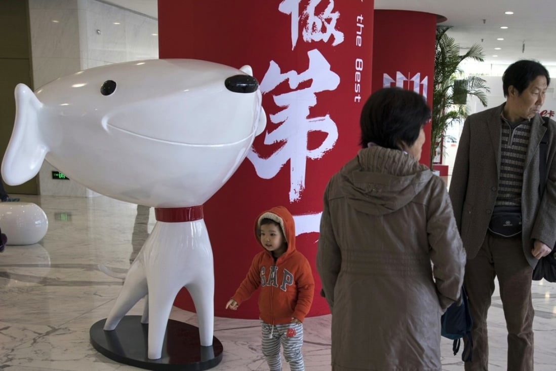 A child stands near the mascot of JD.com and the words for “Be Number One” at the Chinese e-commerce giant’s headquarters in Beijing. JD.com’s investment in Secoo marks its latest deal in the luxury fashion retail market after it paid US$397 million in June last year for a stake in Farfetch, the London-based luxury fashion e-commerce service provider. Photo: AP
