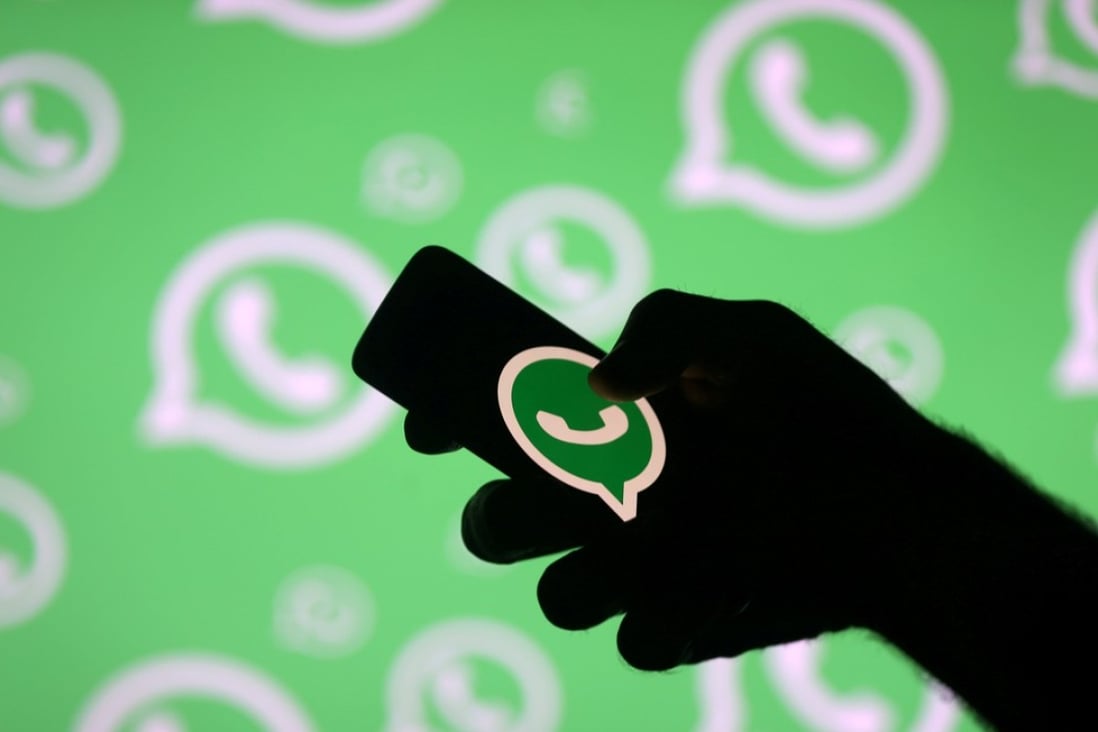 FILE PHOTO: A man poses with a smartphone in front of displayed Whatsapp logo in this illustration September 14, 2017. REUTERS/Dado Ruvic/File Photo