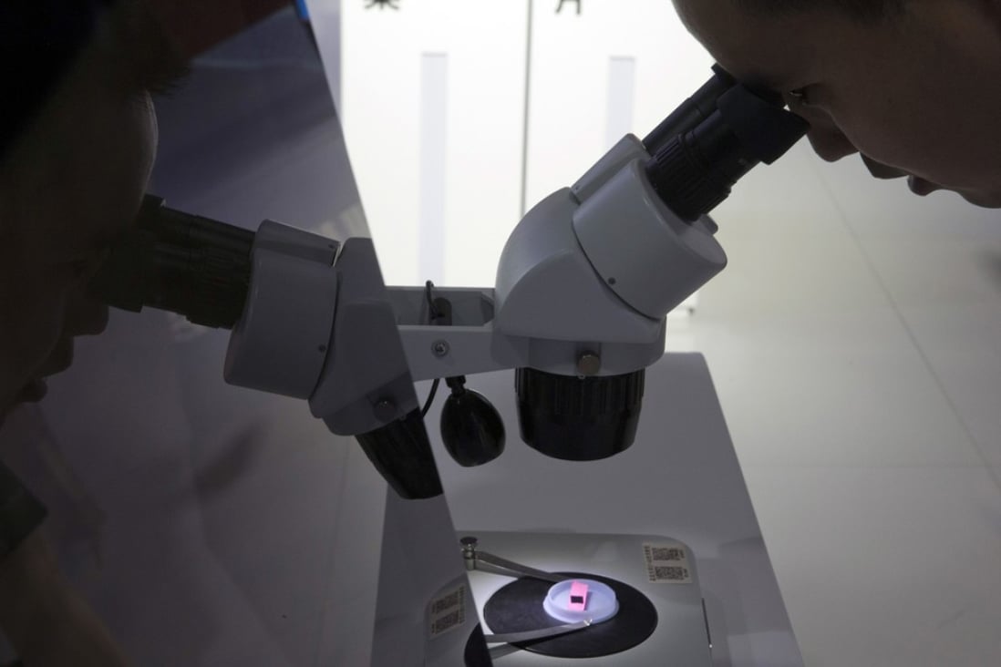 A visitor looks at a computer chip through the microscope displayed by the state-controlled Tsinghua Unigroup project which has emerged as a national champion for Beijing's semiconductor ambitions in China. Photo: AP