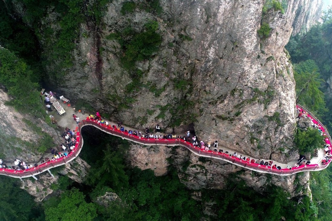 Tourists enjoy a banquet held along the edge of a cliff, at Laojun Mountain in Henan province, China. Amid the US trade war, China’s central bank has had to tread a careful path on monetary policy. Photo: AFP