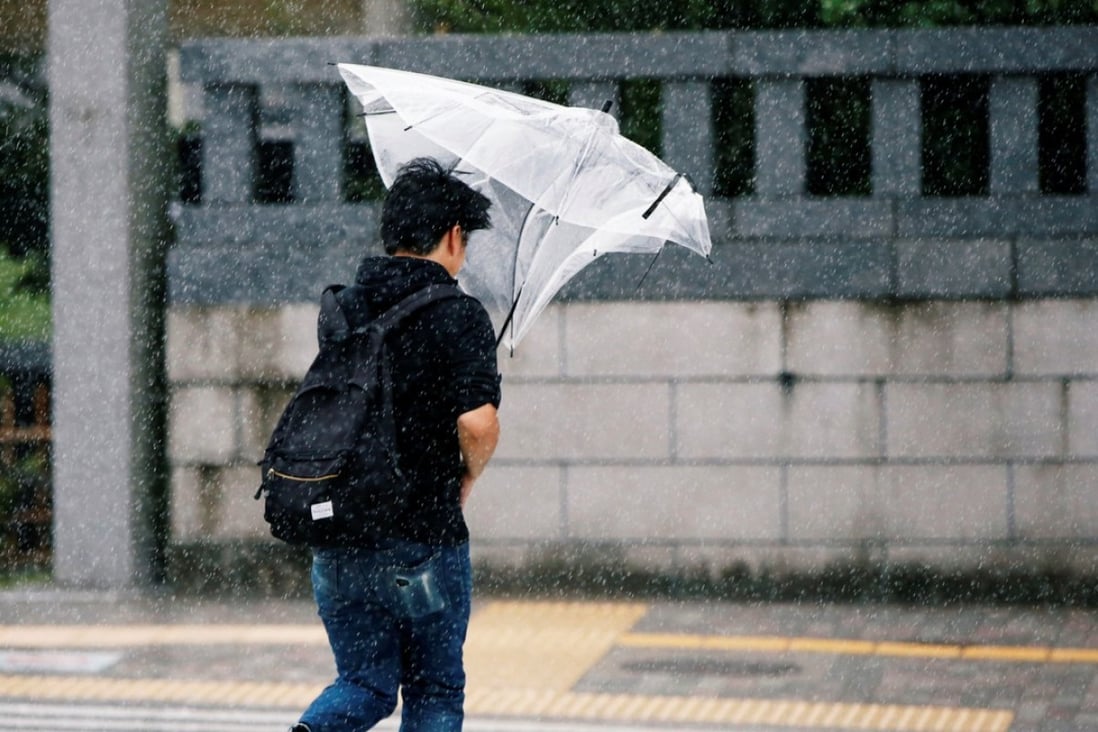 A man struggles to control his umbrella in heavy rain and wind associated with Typhoon Jongdari. Photo: Reuters