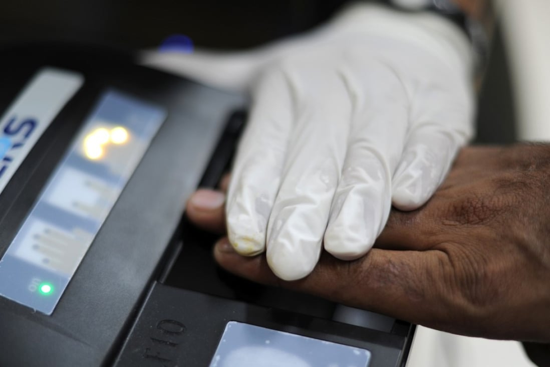 A foreign worker in Malaysia is scanned for a biometric ID at an immigration office. Those who fall foul of immigration rules have told of harsh treatment in holding cells. Photo: AFP
