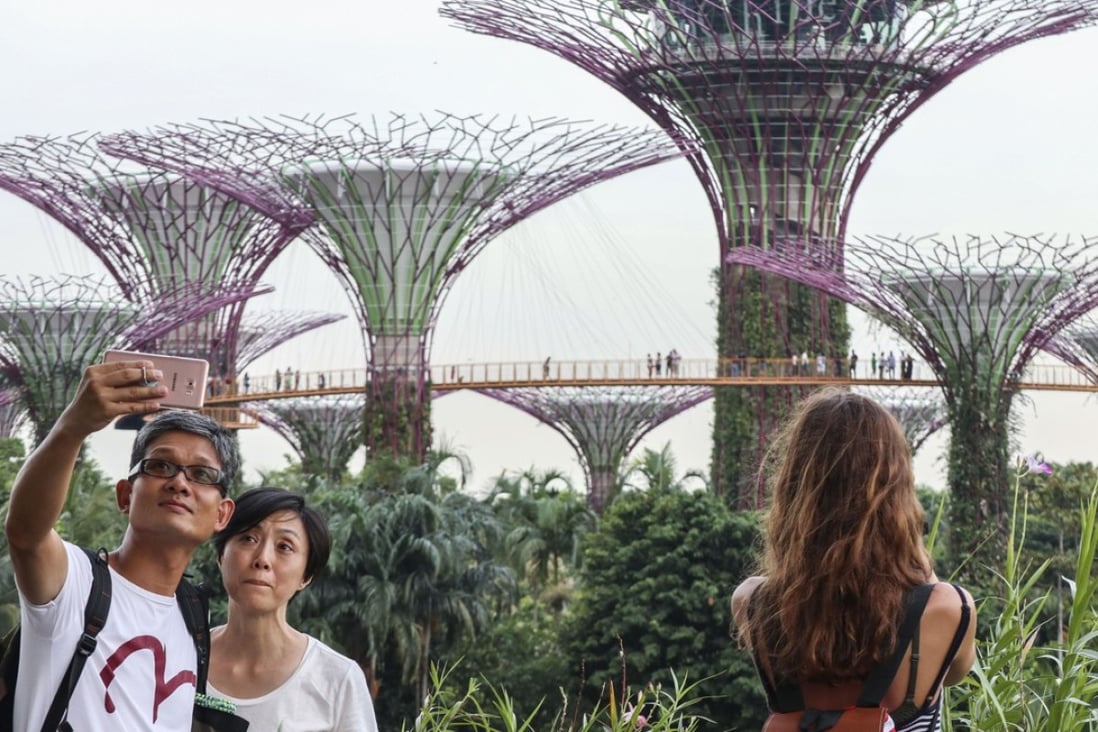Tourists take pictures and selfies of the Supertree Groves at Gardens by the Bay, a nature park in Singapore. A new app lets you pretend to your social media followers that you were somewhere desirable. Roy Issa