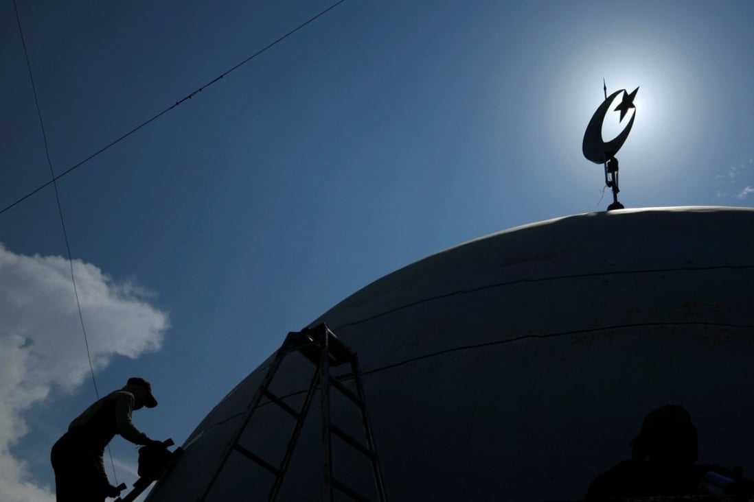 A worker paints the top of a mosque near Lamongan in East Java province. File photo: Reuters
