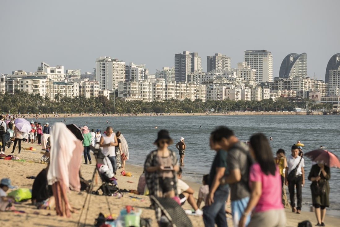 Tourists relax on Sanya Bay beach. Sanya, China’s southern tropical resort city, has introduced the country’s harshest home price cap yet. Photo: Bloomberg