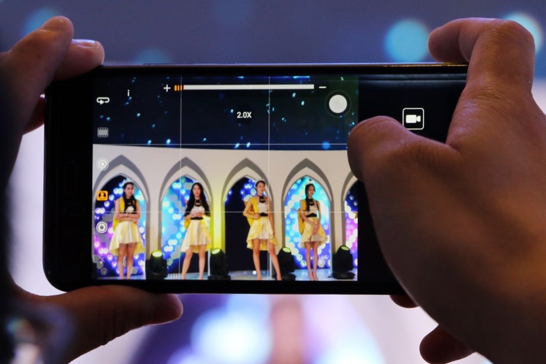 A male attendee takes video of showgirls at the booth of mobile games developer IGN at China's biggest gaming show. Under new rules, all new games will require an operating license. Photo: SCMP/ Zheping Huang