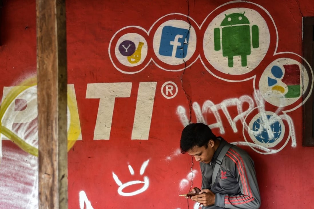A man uses his phone in front of a mobile service provider’s advertisement in Jakarta, Indonesia, in March. Governments in Southeast Asia have ambitious road maps to tap the benefits of the digital economy but have also rushed to regulate it. Photo: AFP