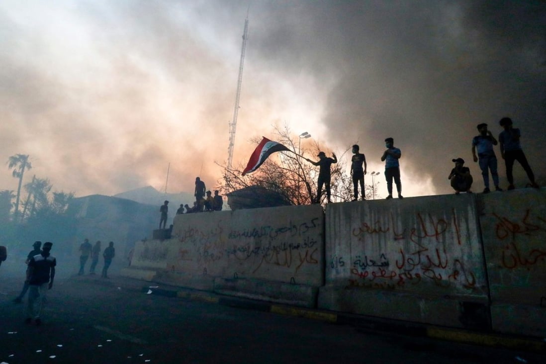 Protesters wave an Iraqi flag while demonstrating outside the burnt-down local government headquarters in the southern city of Basra on September 7, 2018. Photo: AFP