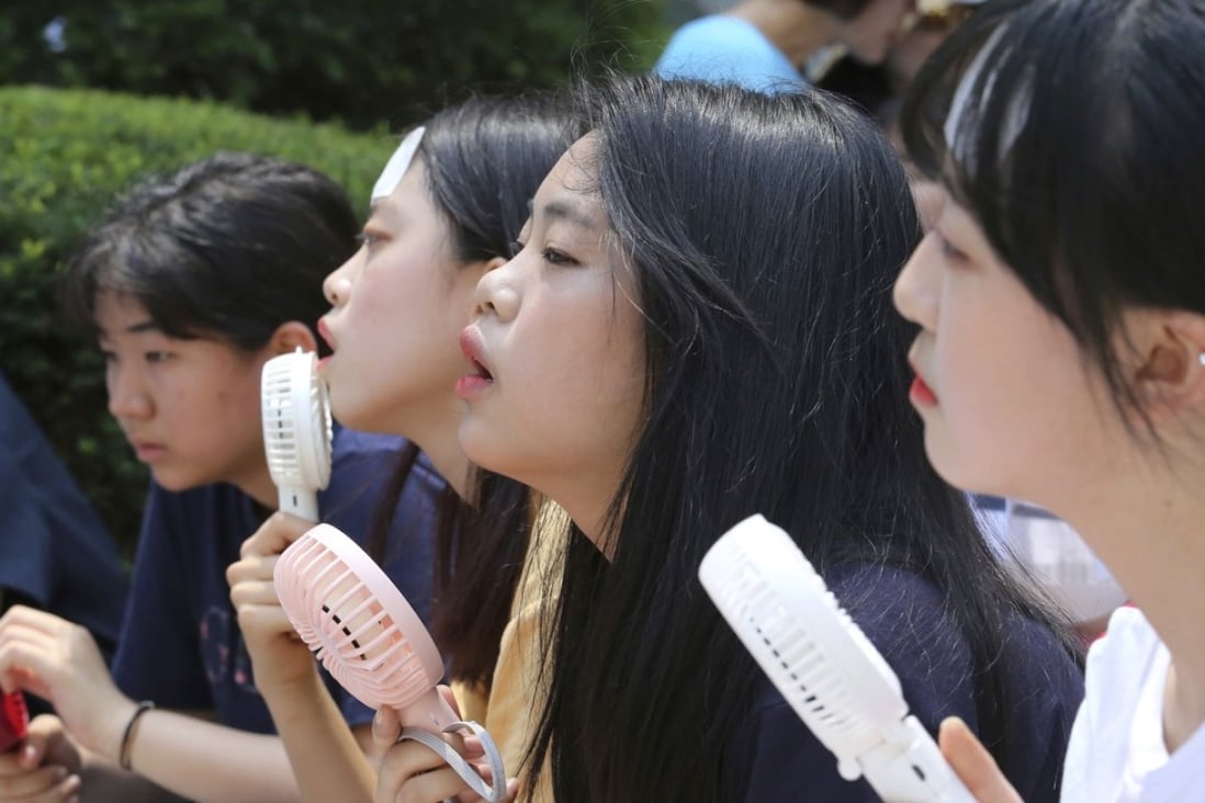 School students use portable fans amid the sweltering heat in Seoul, South Korea, on August 1, 2018. As the trade war escalates, the Korean won could be the next Asian currency to feel the pressure. Photo: AP
