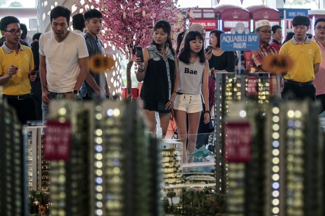 Potential buyers are pictured behind a scale model of Forest City residences in the state of Johor, Malaysia, on March 25, 2018. The development features a hotel, a golf resort, and water front residences built by Guangzhou-based property development company Country Garden: Photo: EPA