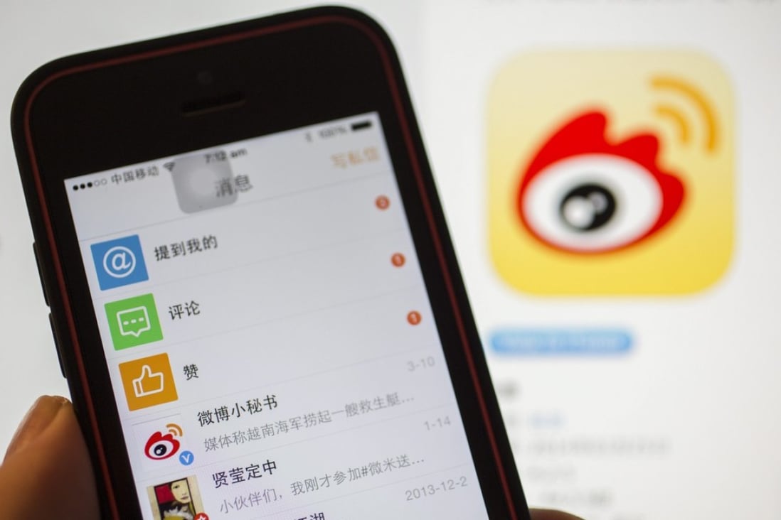 A smartphone running the Sina Weibo social networking app is seen against a background of the company logo on screen in Beijing, China. Photo: EPA