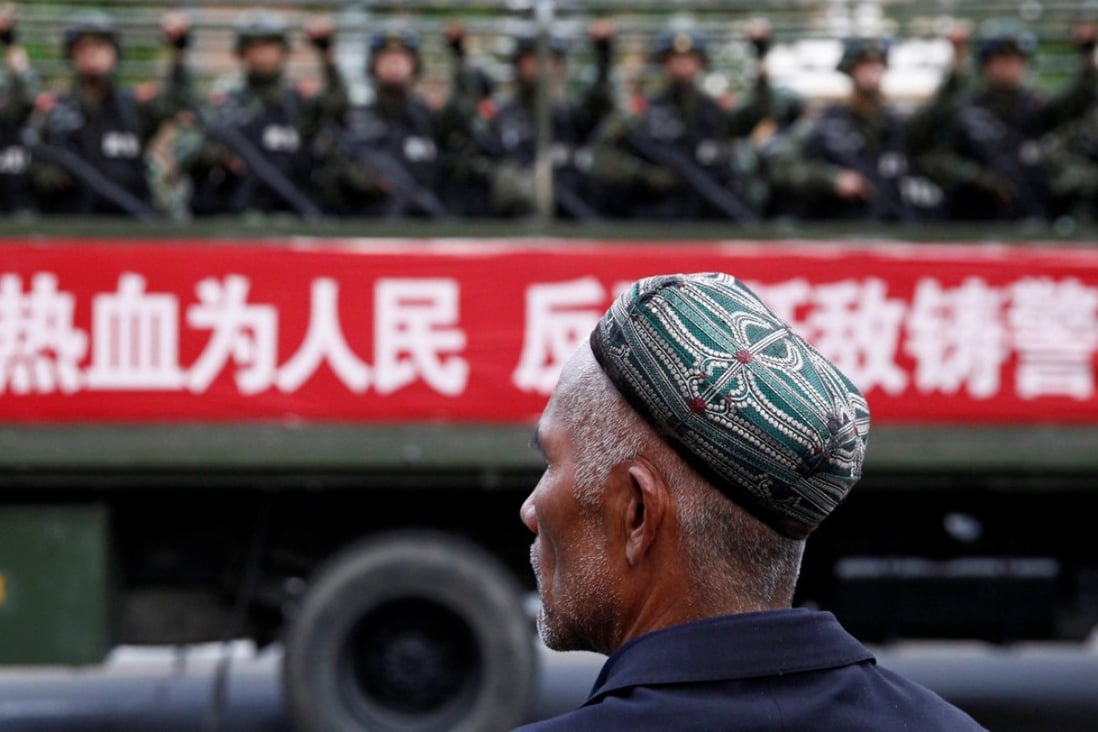 A Uighur man looks on as a truck carrying paramilitary policemen travel along a street during an anti-terrorism oath-taking rally in Urumqi, Xinjiang. Photo: Reuters