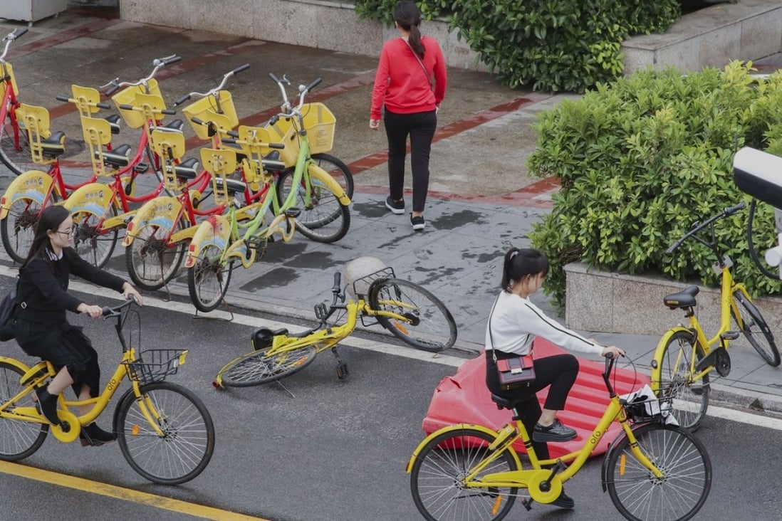 Two women ride bicycles from bike-sharing app operator Ofo in Xiamen, a city in China’s southeastern Fujian province. Photo: Roy Issa