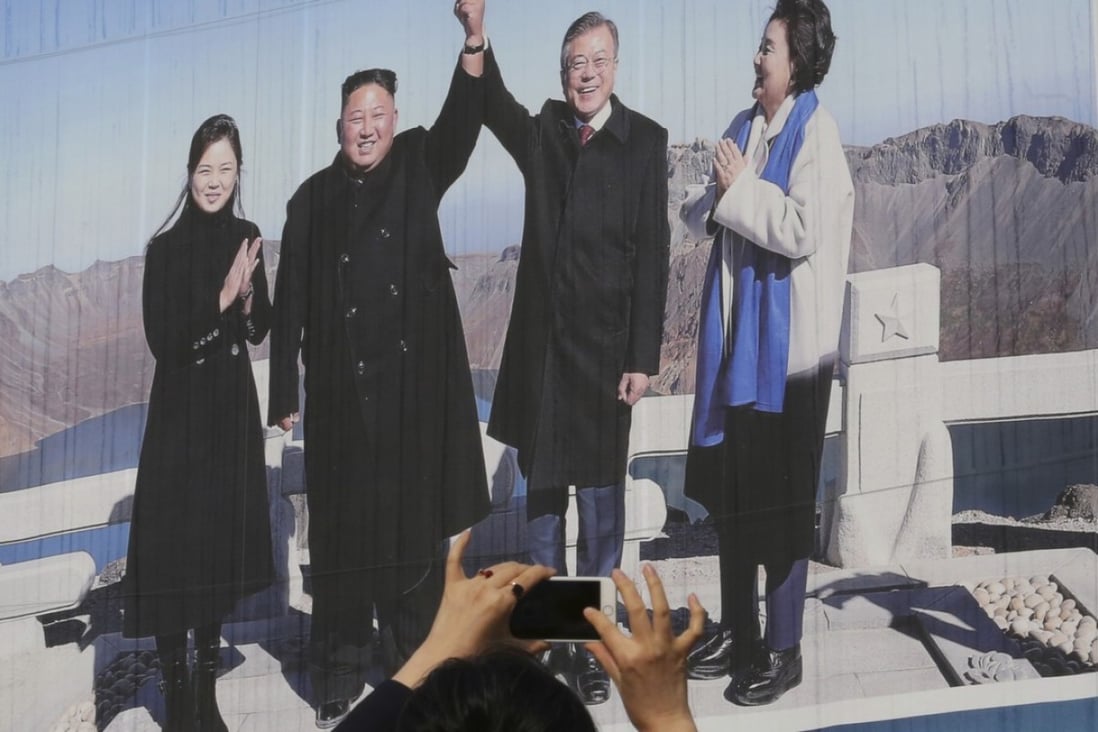 A South Korean woman takes a picture of a banner showing South Korean President Moon Jae-in and his wife Kim Jung-sook with North Korean leader Kim Jong-un and his wife Ri Sol-ju on North Korea's Mount Paektu. Photo: AP