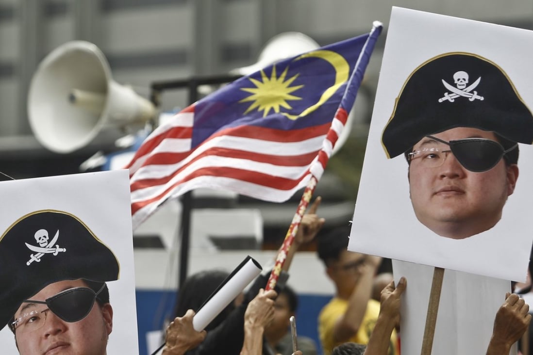 Portraits of Jho Low held aloft during a protest in Kuala Lumpur, Malaysia. Photo: AP