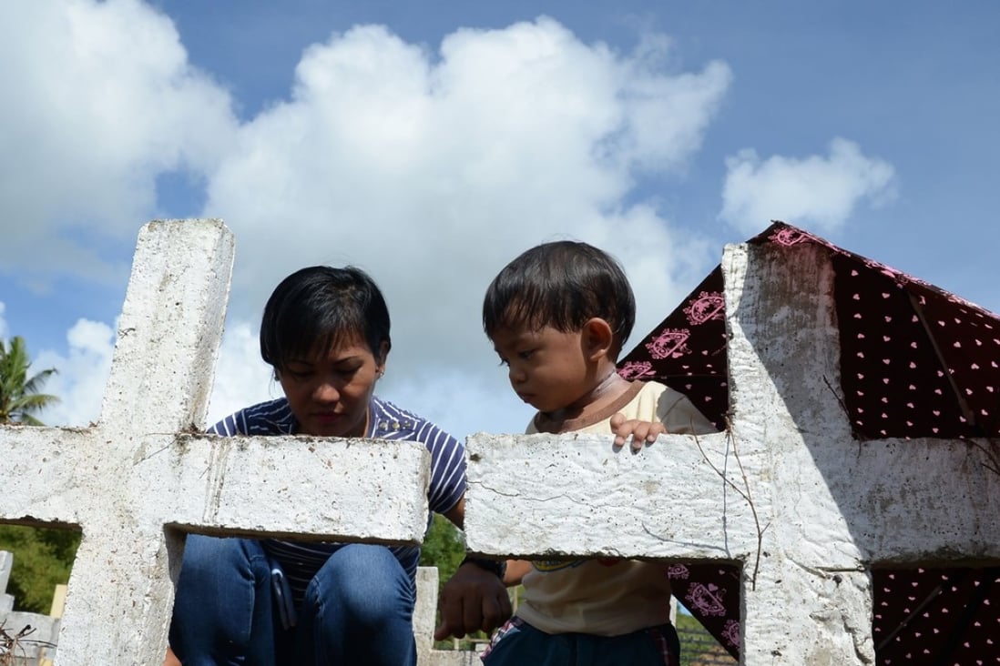 Juvilyn Luana and her son visit the graves of family members who died in Typhoon Haiyan. Photo: AFP