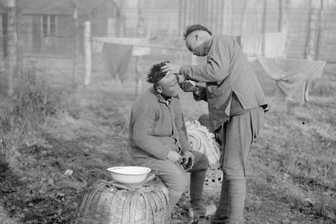 A barber at work at a Chinese labour camp in Crécy Forest, France, in January 1918. Picture: Alamy