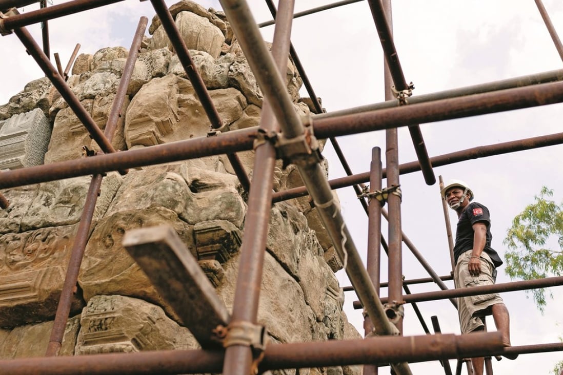 Stonemason Morm Pum, who has been working in temple restoration since 1993, stands on top of a scaffolding at West Mebun temple, Angkor, Cambodia, before work on it was halted. Photo: Enric Catala