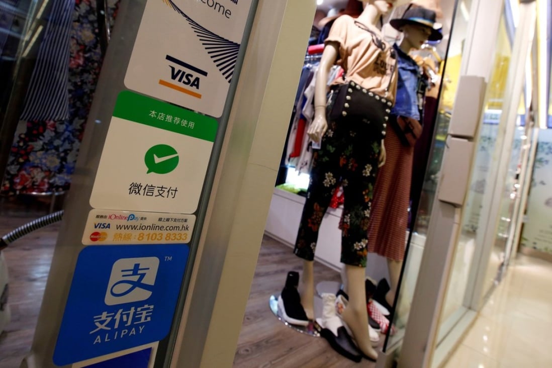 Logos of digital payment services, including WeChat Pay, are displayed outside a boutique at a shopping mall in Hong Kong. Photo: Reuters