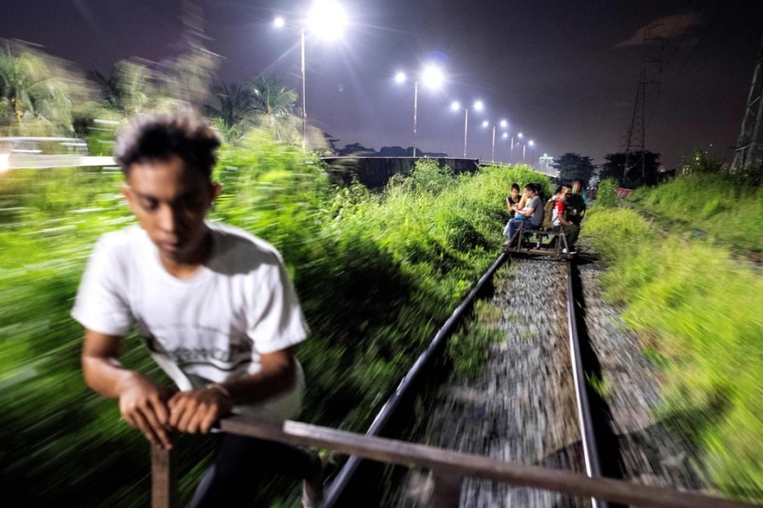 A ‘trolley boy’ pushes a home-made cart along a train track in Manila. Photo: AFP