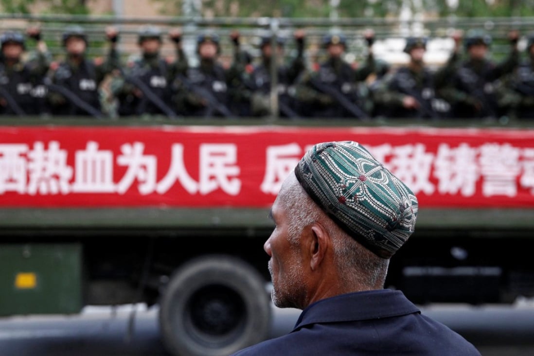 A Uygur man watches as a truck carrying paramilitary policemen passes by in Xinjiang. Photo: Reuters