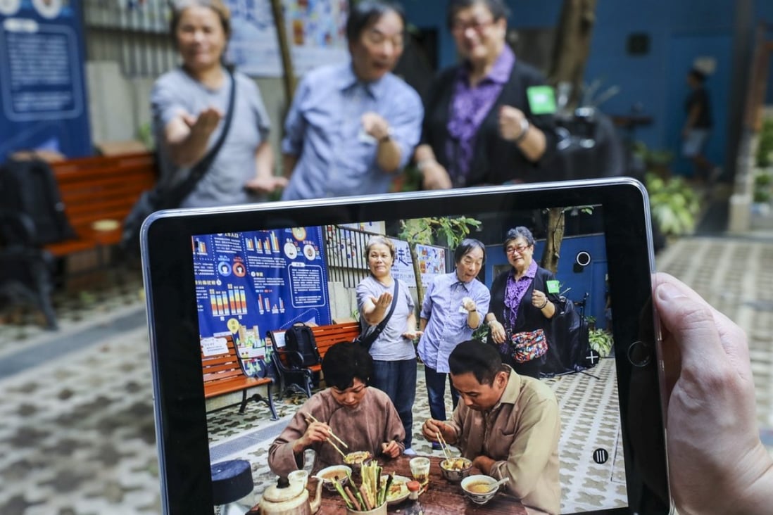 Masaki Fujihata’s augmented reality app in action. Toon Lai-ning, 66, (back, left) and Jannie Wong Yuk-chun, 69, (back, right) lived in Wan Chai for decades and they shared their stories with Fujihata (back, centre) for him to create the AR figures. Photo: Dickson Lee