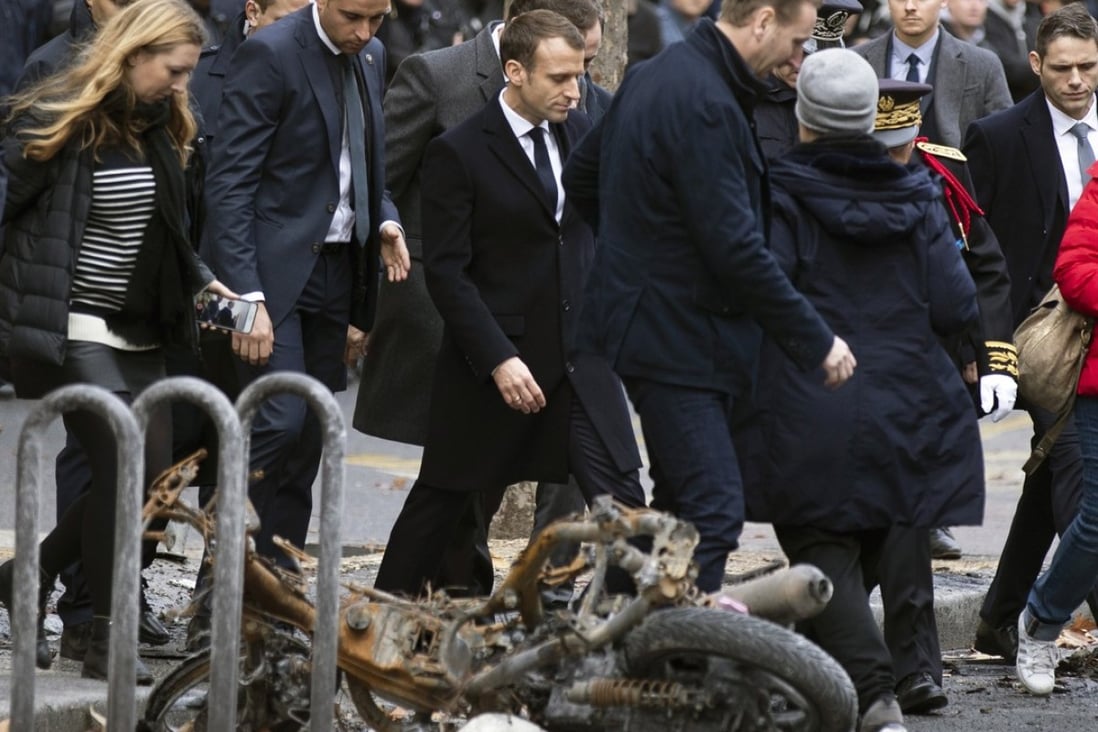 French President Emmanuel Macron walks past a torched motorbike near the Champs Elysee in Paris, France on December 2, 2018. Photo: EPA