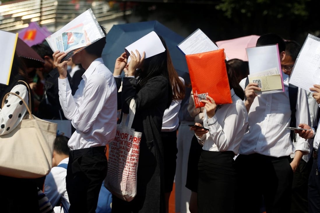 Students shield themselves from the sun as they line up at a job fair at a Guangzhou university last week. There are signs that China’s jobs market is weakening. Photo: Reuters