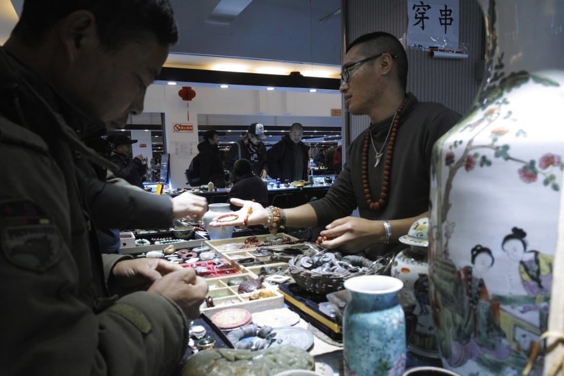 A vendor talks with customers at the Panjiayuan antique market in Beijing. Photo: EPA