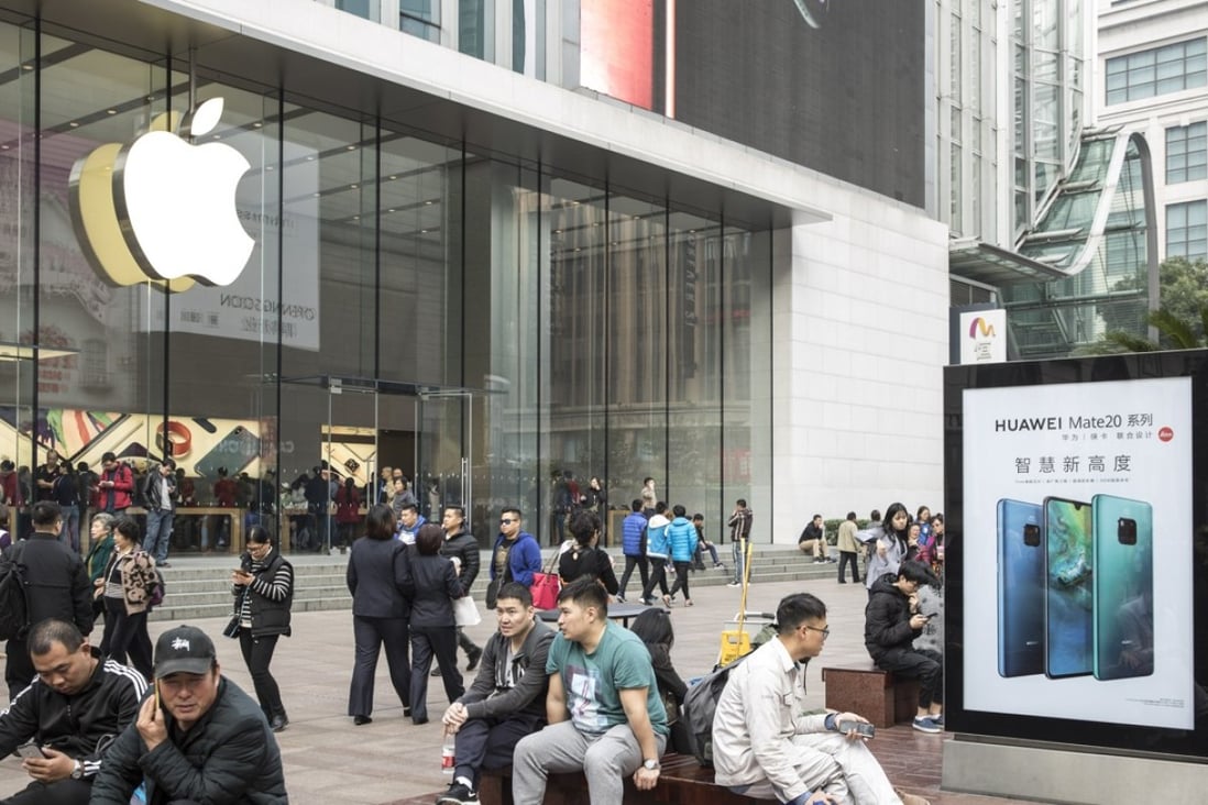 People sit on benches near an advertisement for the Huawei Technologies Co. Mate 20 smartphone outside an Apple Inc. store in Shanghai, China, on Tuesday, Nov. 27, 2018. Photo: Bloomberg
