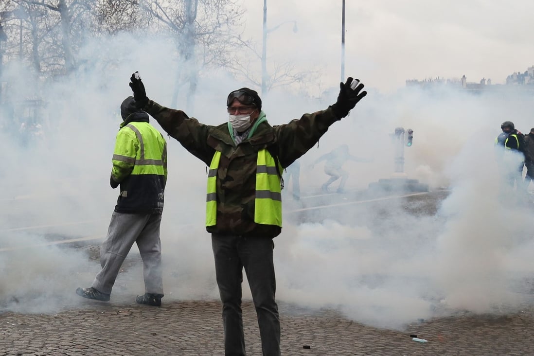 Yellow Vest protesters stand amid tear gas as they clash with police during an anti-government demonstration called by the Yellow Vest movement in Paris. Photo: AFP