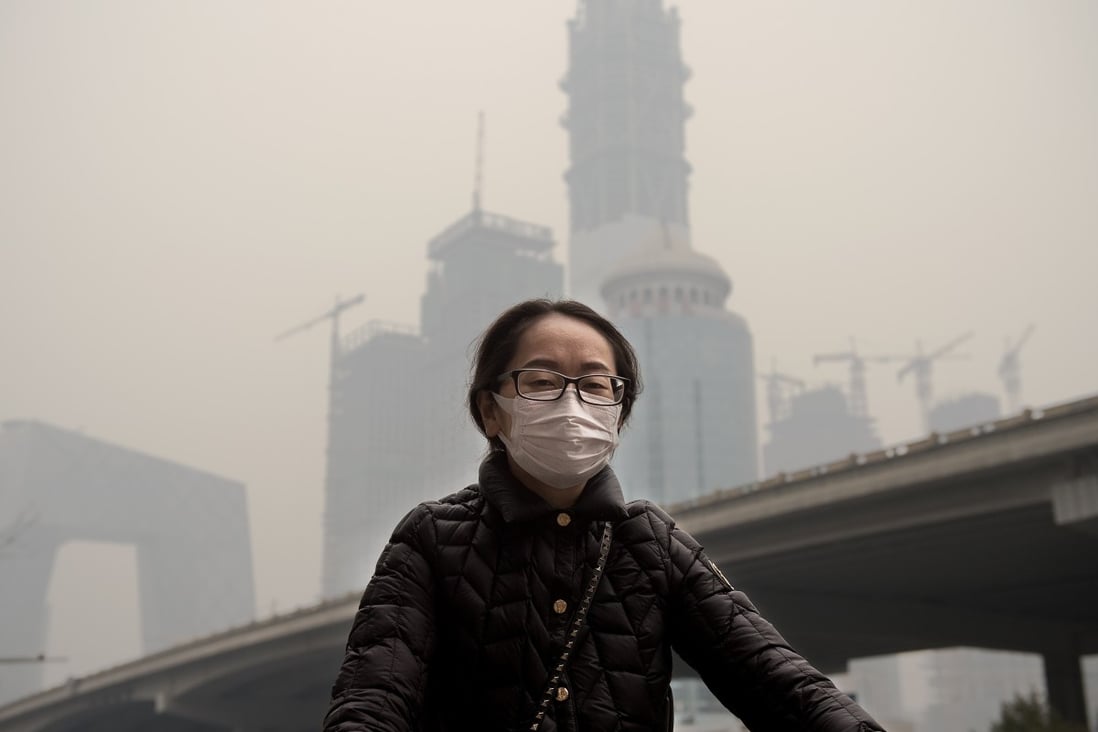A woman wearing a protective pollution mask cycling in Beijing through thick smog. Photo: AFP