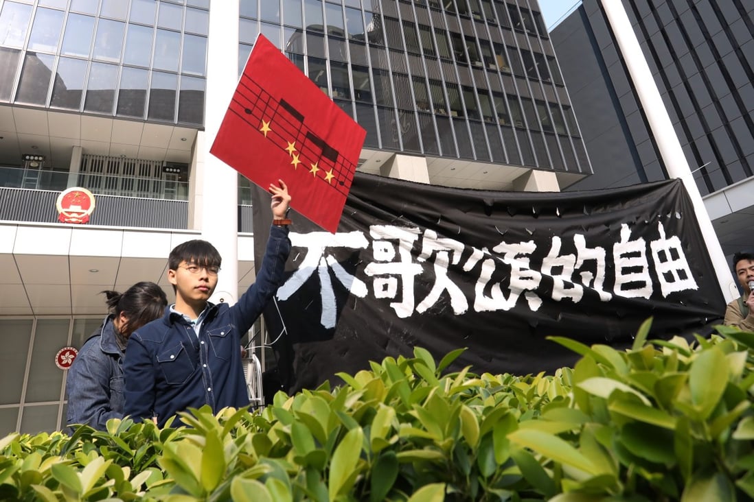 Joshua Wong and other members of his Demosisto party display a banner reading “Freedom not to sing praises” outside the Hong Kong government headquarters. Photo: Dickson Lee