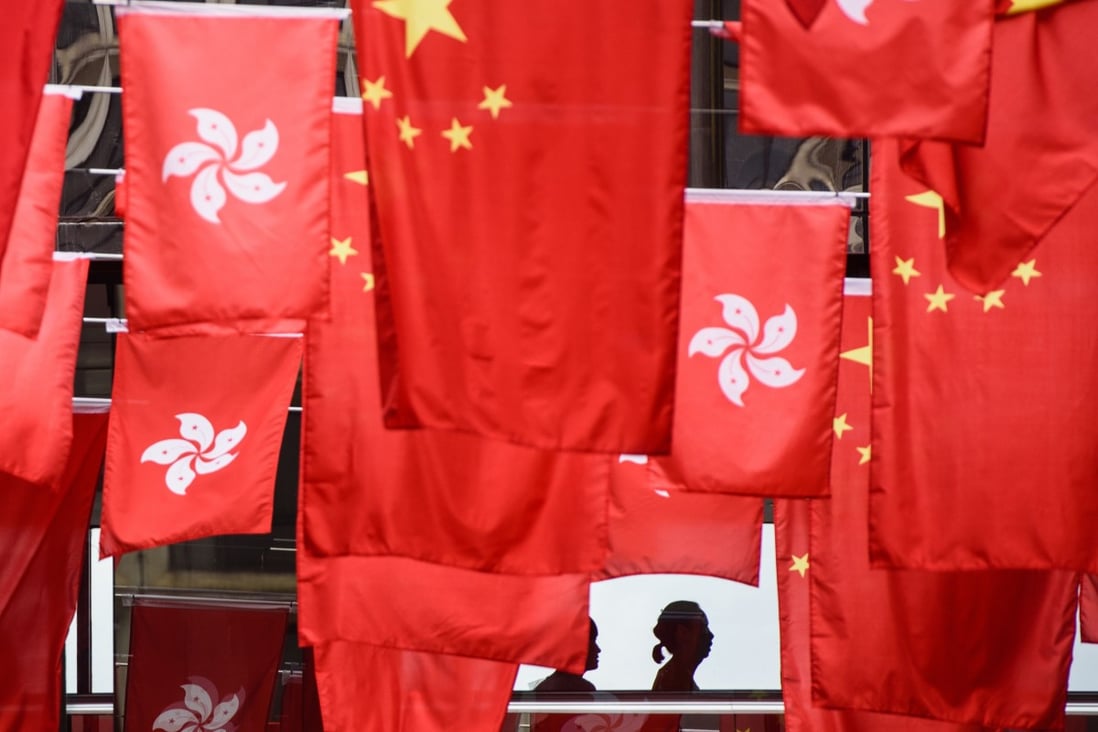 People walk past a display of China’s national flags and those of Hong Kong, ahead of the 20th anniversary of the city's handover from Britain to China. Photo: AFP