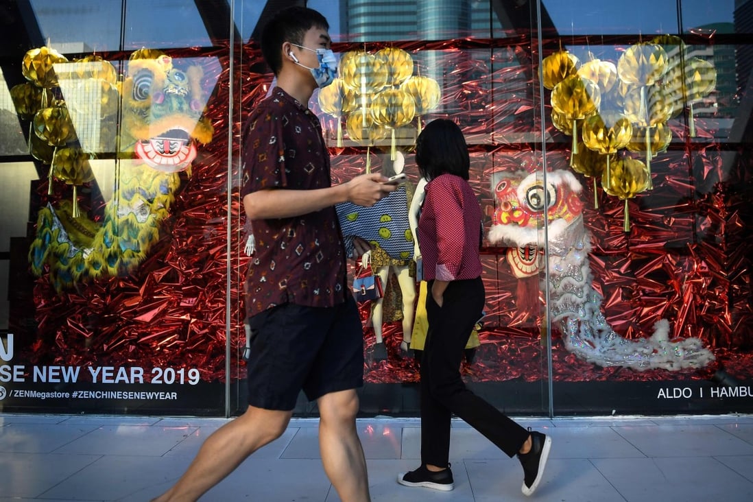 Chinese tourists walk past a Lunar New Year-themed display at a shopping centre in Bangkok, Thailand, on February 5, 2019. Photo: Agence France-Presse