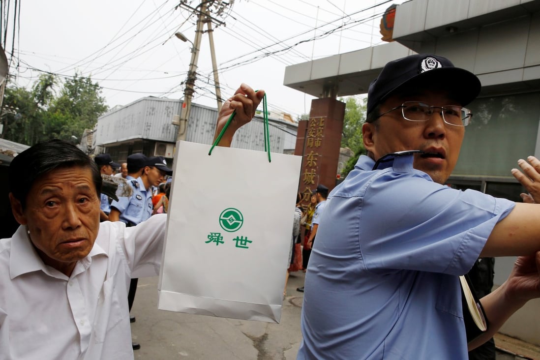 A man holds up a bag with a logo of a P2P lender as he attends a protest over losses incurred in peer-to-peer (P2P) investment schemes in front of the public security ministry of Dongcheng district in Beijing on August 27, 2018. Photo: Reuters