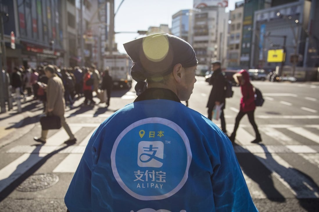 A staff member wearing a uniform featuring the logo for Ant Financial Services Group's Alipay, an affiliate of Alibaba Group Holding, during a campaign event in Tokyo on December 9, 2017. Photo: Bloomberg
