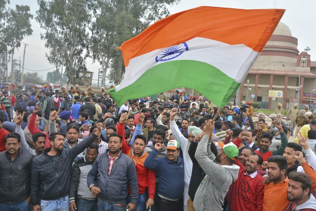 Supporters of the captured Indian pilot wave their country’s national flag in anticipation of his return. Photo: AP