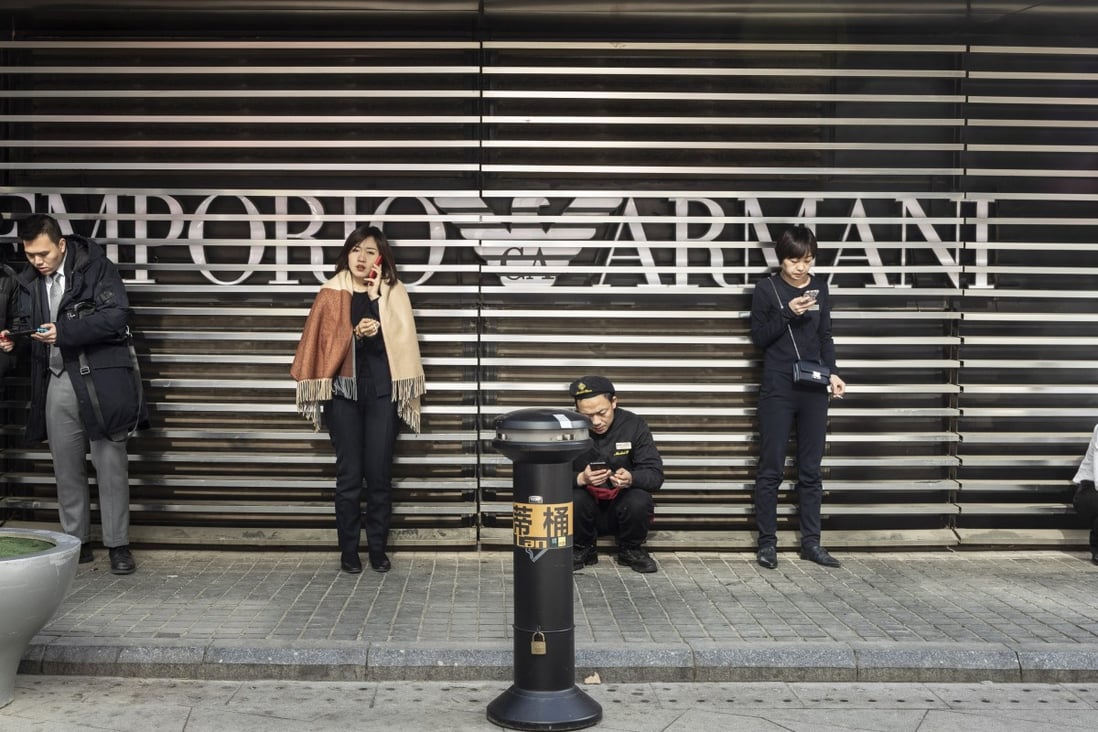 Pedestrians use smartphones outside an Emporio Armani store in Beijing. Soft trade data is a better indicator of China’s economic health than GDP numbers. Photo: Bloomberg
