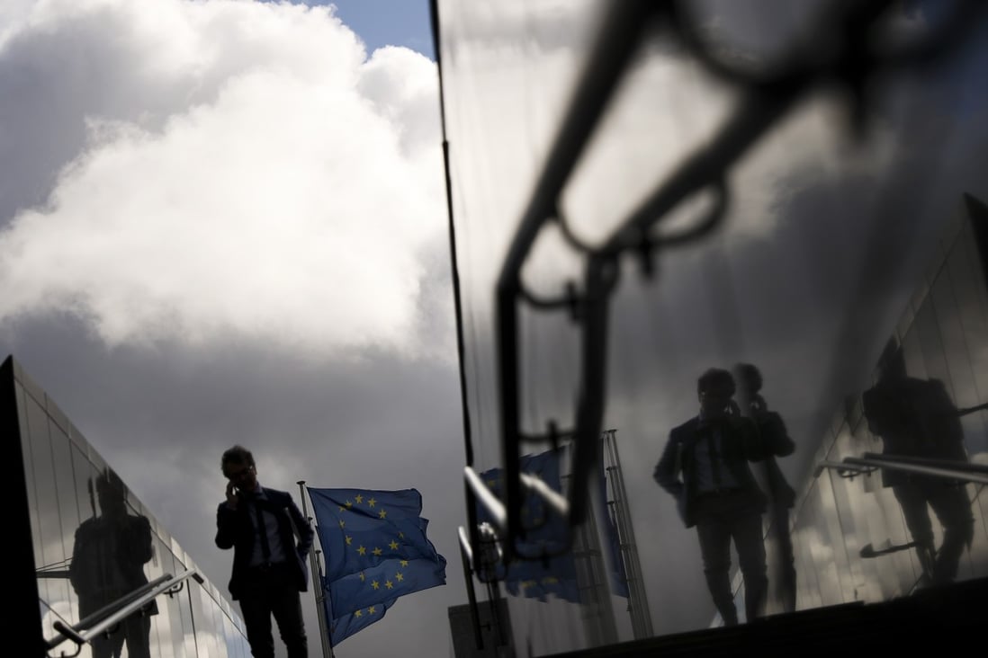 A man walks past European Union flags outside the European Commission headquarters in Brussels. Photo: AP Photo